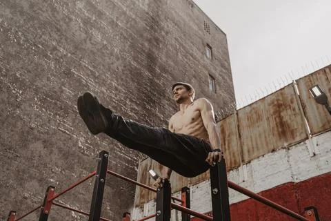 Young man doing parallel bars abdominal exercise. Stock Photos