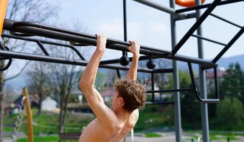 Young Man Doing Pull-Up Exercise Outdoors Stock Photos