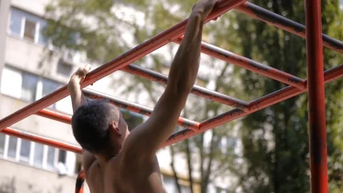 Young man is doing pull ups on the exercise ladder from the back Stock Footage 79278033