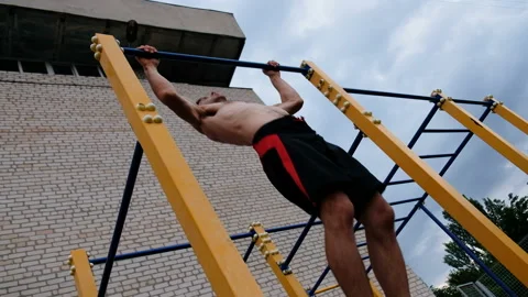 Young man doing pull ups on horizontal bar outdoors Stock-Footage 92052729
