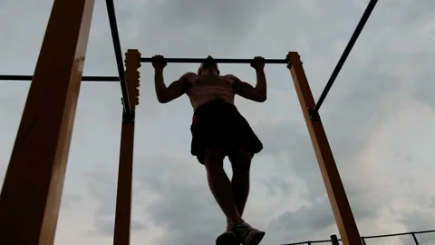 Young man doing pull ups on horizontal bar outdoors 스톡 동영상 92052748