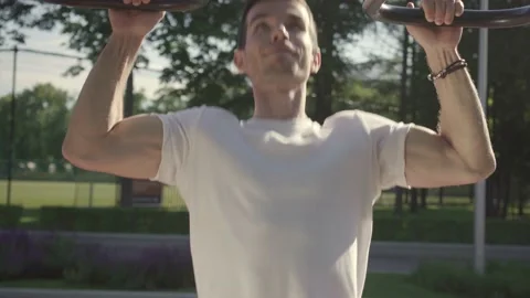 Young man doing pull-ups on horizon bar on sports ground Stock Footage 146305161