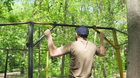 Young Man Doing Pull Ups on Bar on Sunny Day in City Park Stock Footage 276135925