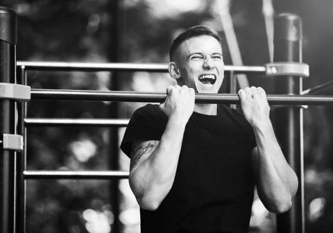 Young man doing pull ups on horizontal bar outdoors, workout, sport concept Stock Photos