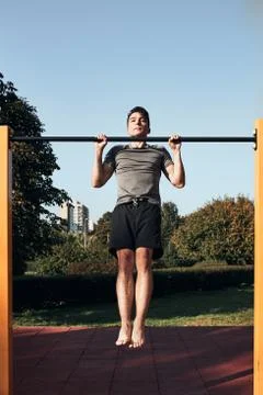 Young man doing pull-ups during his workout in a modern calisthenics street w Stock Photos