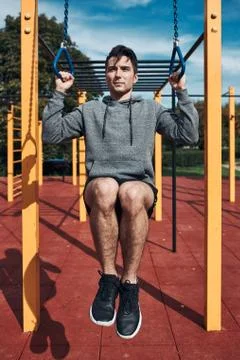 Young man doing pull-ups during his workout in a modern calisthenics street w Stock Photos