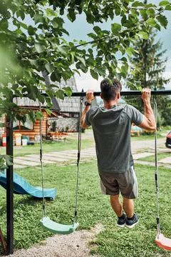 Young man doing pull-ups on pull-up horizontal bar during his calisthenics wo Stock Photos