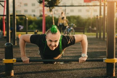 Young man doing push-up exercise on the street on an iron bar Stock Photos