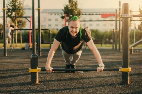 Young man doing push-up exercise on the street on an iron bar Stock Photos