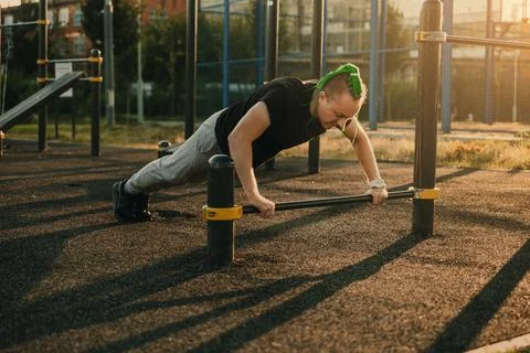 Young man doing push-up exercise on the street on an iron bar Stock Photos