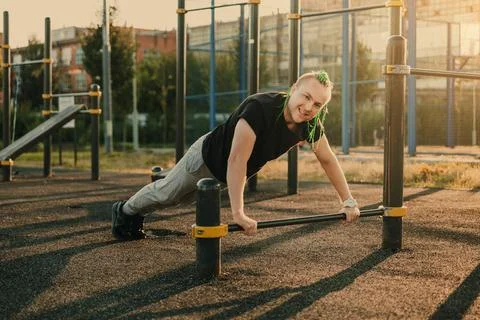 Young man doing push-up exercise on the street on an iron bar Stock Photos