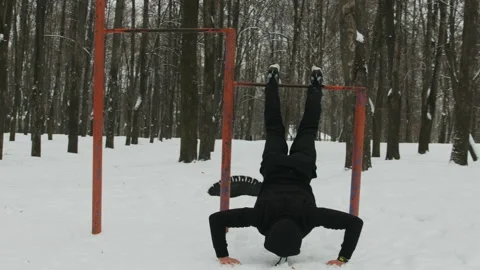 Young man doing push-UPS with a horizontal bar, gymnastics outdoors in winter Stock Footage 111161558