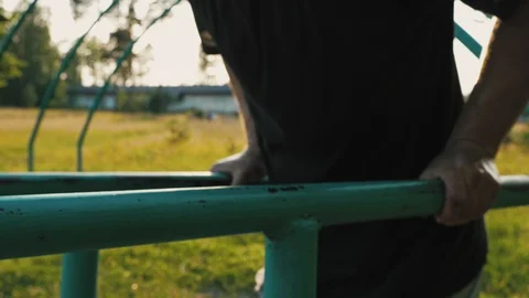 Young man doing push-ups from parallel bars on the playground in a natural Video stock 112778214