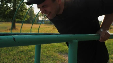 Young man doing push-ups from parallel bars on the playground in a natural Stock Footage 112778555