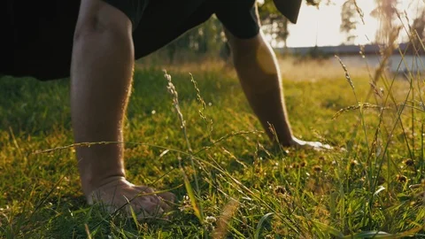 Young man doing push-ups on the lawn in a natural public park. Stockbeeldmateriaal 112778887
