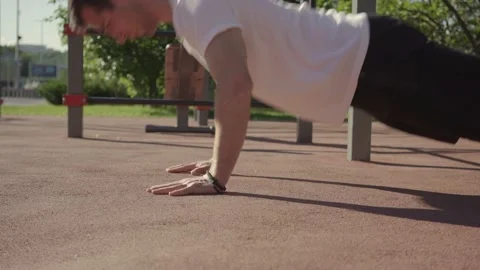 Young man doing push-ups on sports ground Stock Footage 146305853