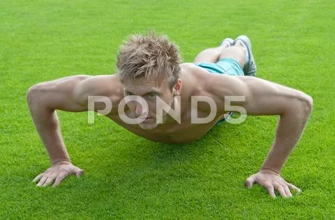 Young man doing push-ups on green grass Stock Photos