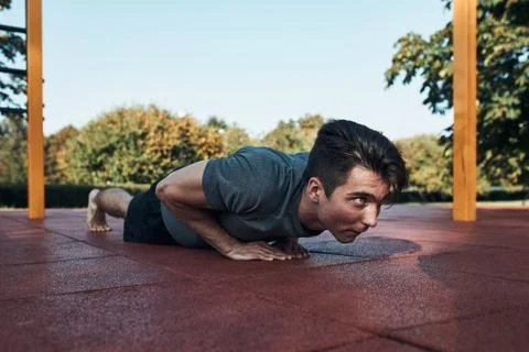 Young man doing push-ups on a red rubber ground during his workout in a moder Stock Photos