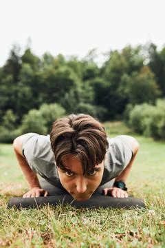 Young man doing push-ups outside on grass during his calisthenics workout Foto stock