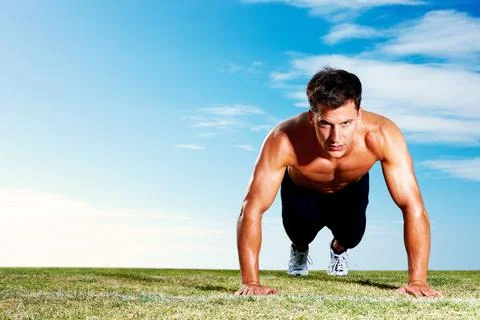 Young man doing pushups on the field - Copyspace. Portrait of a young man doing Stock Photos