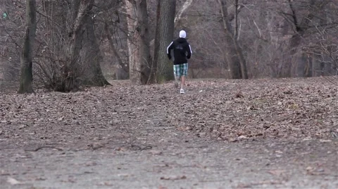 Young man doing running exercise upon morning forest road Stock Footage 59843145