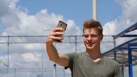 Young man doing selfies on the platform while waiting for his train Stock Footage 78655314