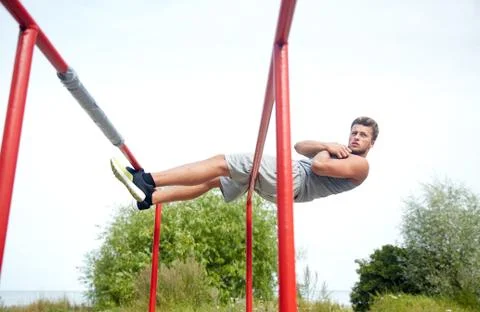 Young man doing sit up on parallel bars outdoors 写真素材