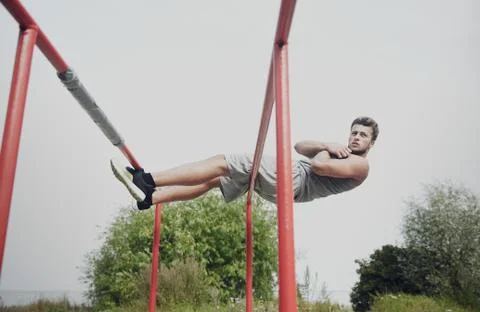 Young man doing sit up on parallel bars outdoors Stock Photos