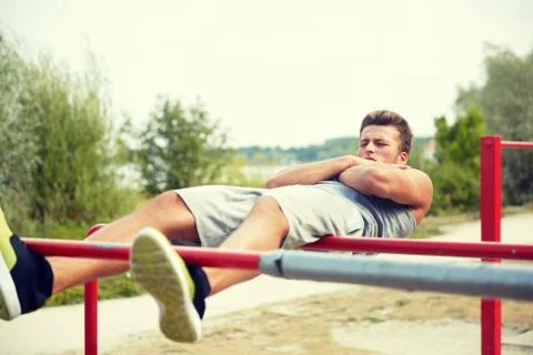 Young man doing sit up on parallel bars outdoors 写真素材