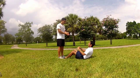 Young man doing sit-ups, exercising with personal trainer Stock Footage 27923039