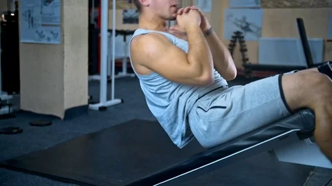 Young man doing sit-ups on abdominal bench and getting tired abdominal exercises Stock Footage 81422670
