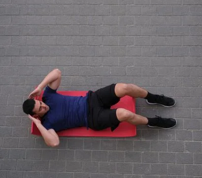 Young man doing sit-ups on a red mat. Stock Photos