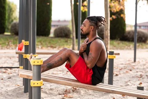 Young man doing sit-ups during workout in a calisthenics street workout park Stock Photos