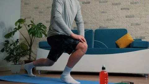 Young man doing sport exercises at home on a blue mat. Stock Footage 148945151