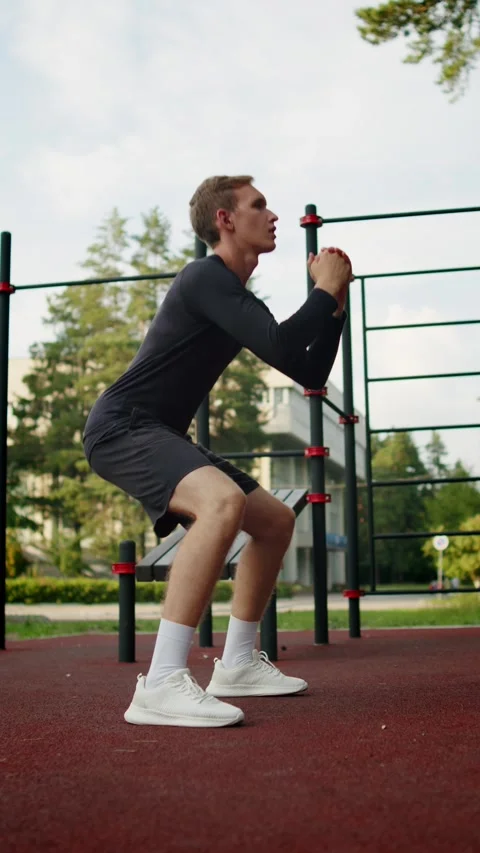 Young man doing squats at an outdoor gym. Athletic man training leg muscles.. Stock Footage 341728225