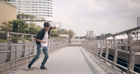 Young man doing street dancing in front of pier with unidentified people walking Stock Footage 106374391