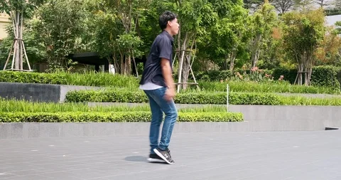 Young man doing street dancing mood walk with green trees and garden in Stock Footage 106374540