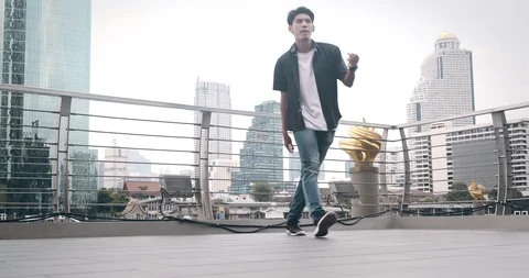 Young man doing street dancing in front of pier in background. Asian man. Stock Footage 106374829