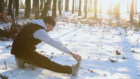Young man doing stretching exercises during winter training outside in cold Stockbeeldmateriaal 77036331