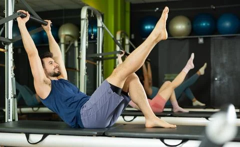 Young man doing teaser exercise on pilates reformer Fotos Stock