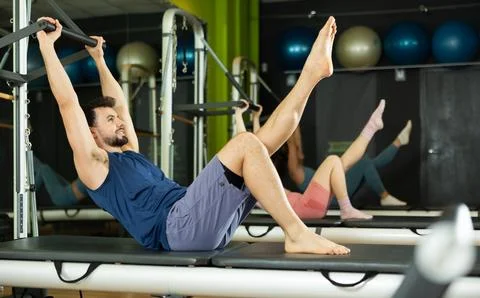 Young man doing teaser exercise on pilates reformer Fotos Stock