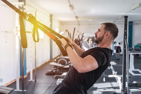 Young man doing TRX exercises at the gym. TRX training. Sport and fitness. Cr Foto stock
