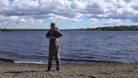 Young man doing warm-up to workout on the shore of a lake . Stock Footage 90942170