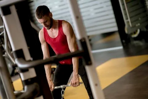 Young man doing workouts for a back with power exercise machine in a gym club Stock Photos