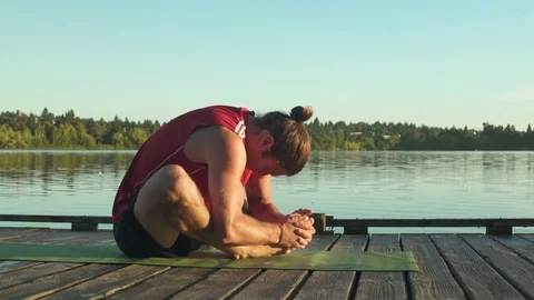 A young man doing yoga on a dock 動画素材 76223386