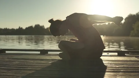 A young man doing yoga on a dock at sunrise Stock-Footage 76223590
