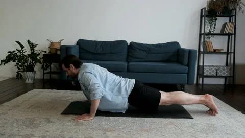 A young Man Is doing Yoga doing Push UPS On the Floor of The house Stock Footage 144242327