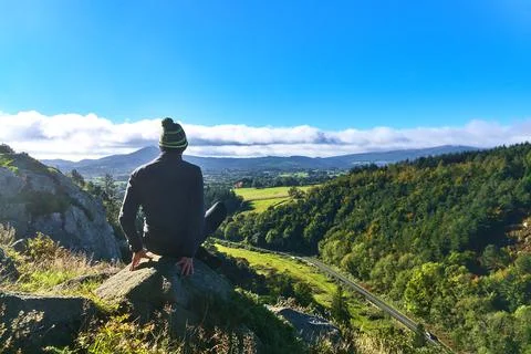 Young man doing yoga exercise and looking at the beautiful scenic mountains Stock Photos
