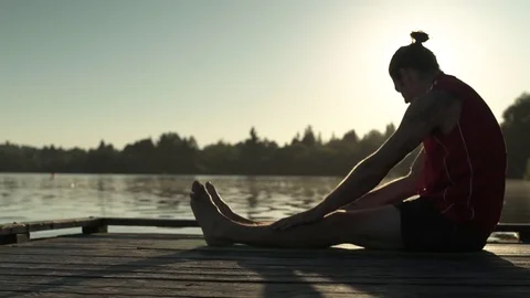 A young man doing yoga on a pier at sunrise 動画素材 76223537