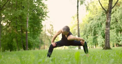Young man doing yoga pose ina park at morning. Guy doing stretching. Slow motion Stock Footage 156981427